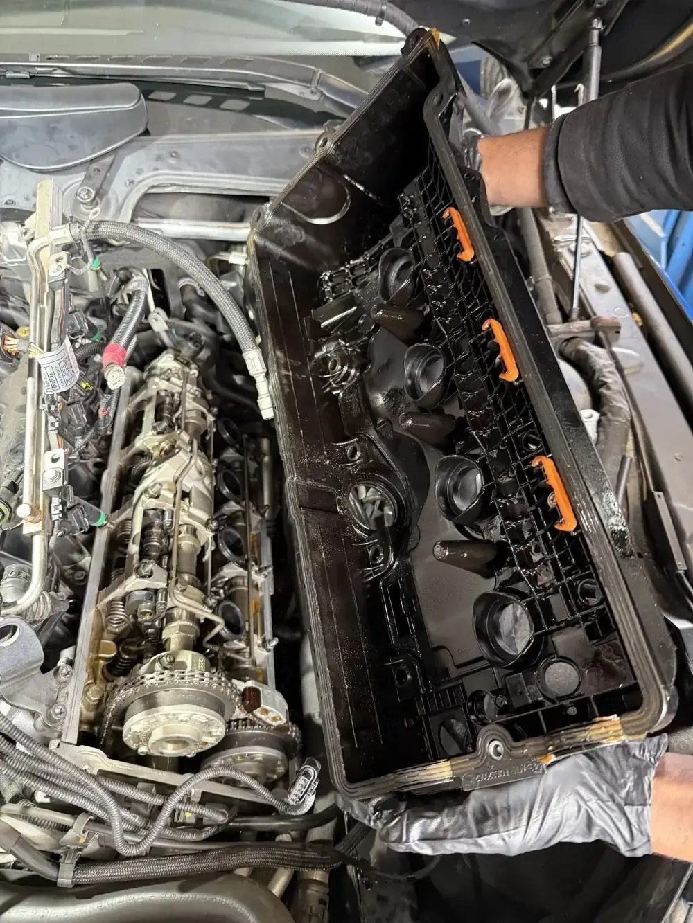 BMW N62 valve cover removed exposing the cylinder head, camshafts, and valvetrain during cover replacement at Beacon Auto Care San Mateo