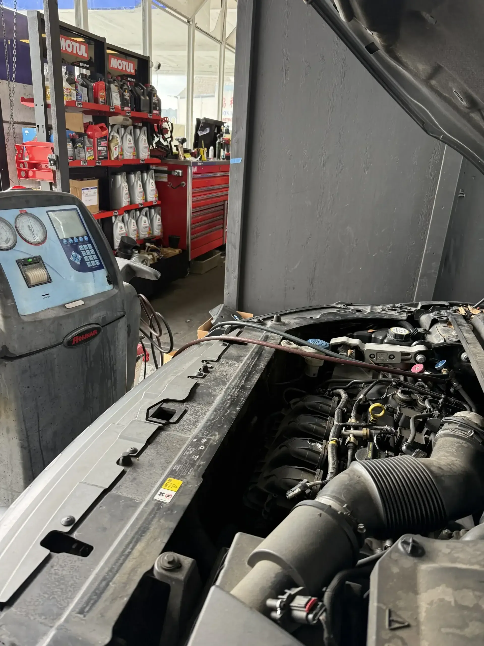 Ford engine bay AC service with Robinair recharge machine connected at Beacon Auto Care San Mateo