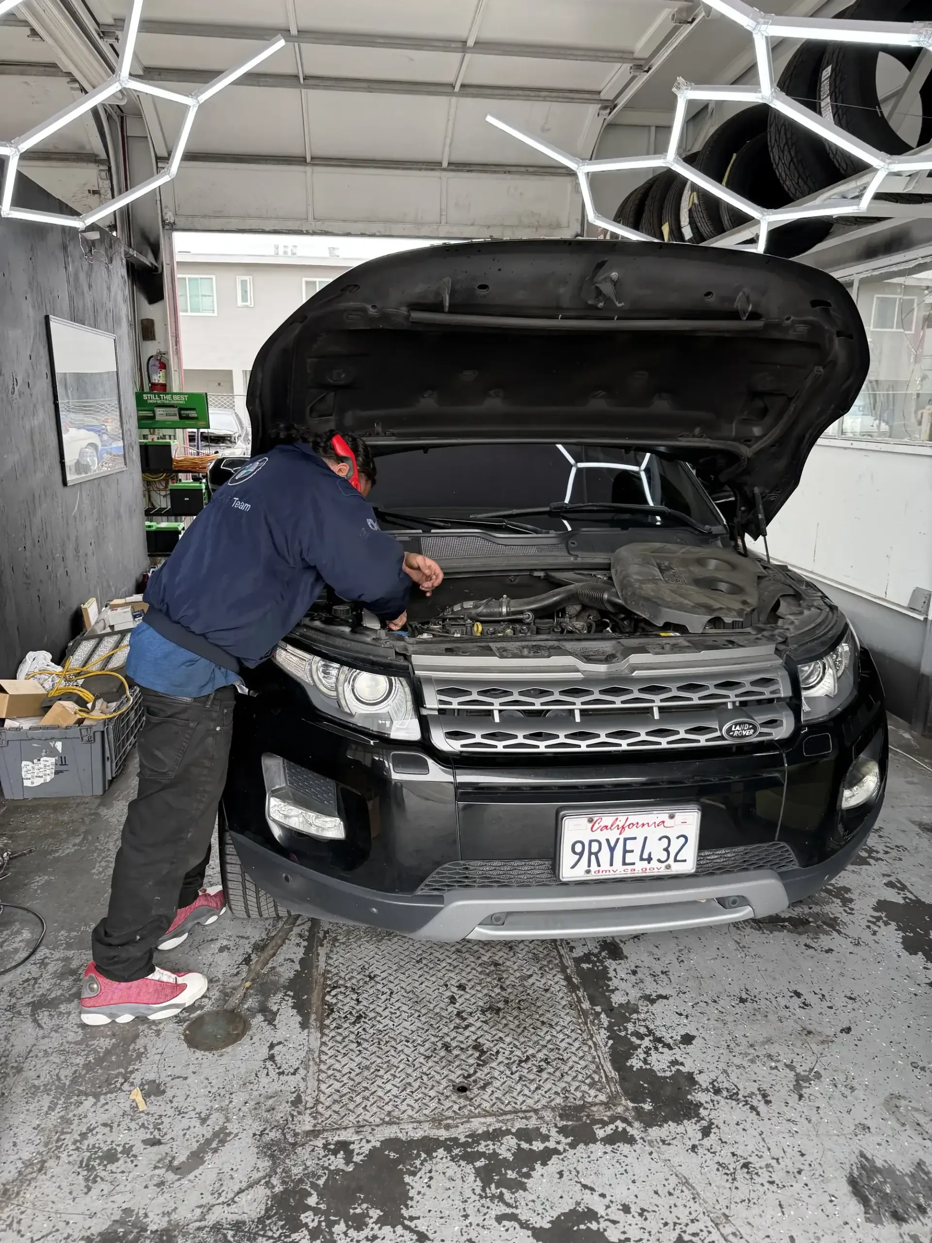 Favio, lead mechanic at Beacon Auto Care San Mateo, leaning into the engine bay of a Range Rover Evoque diagnosing a fault